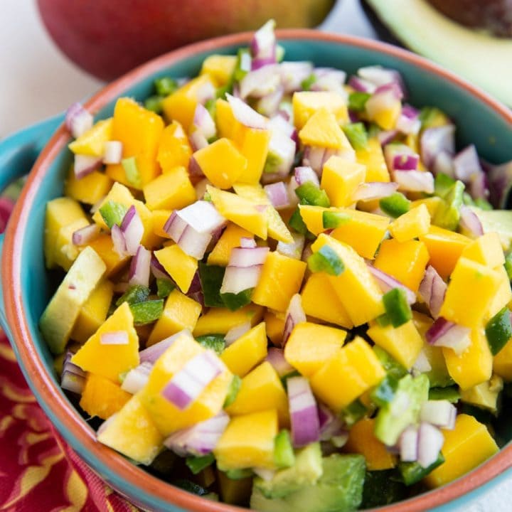 Blue bowl of mango avocado salsa, ready to be enjoyed on top of fish tacos or chicken breasts.