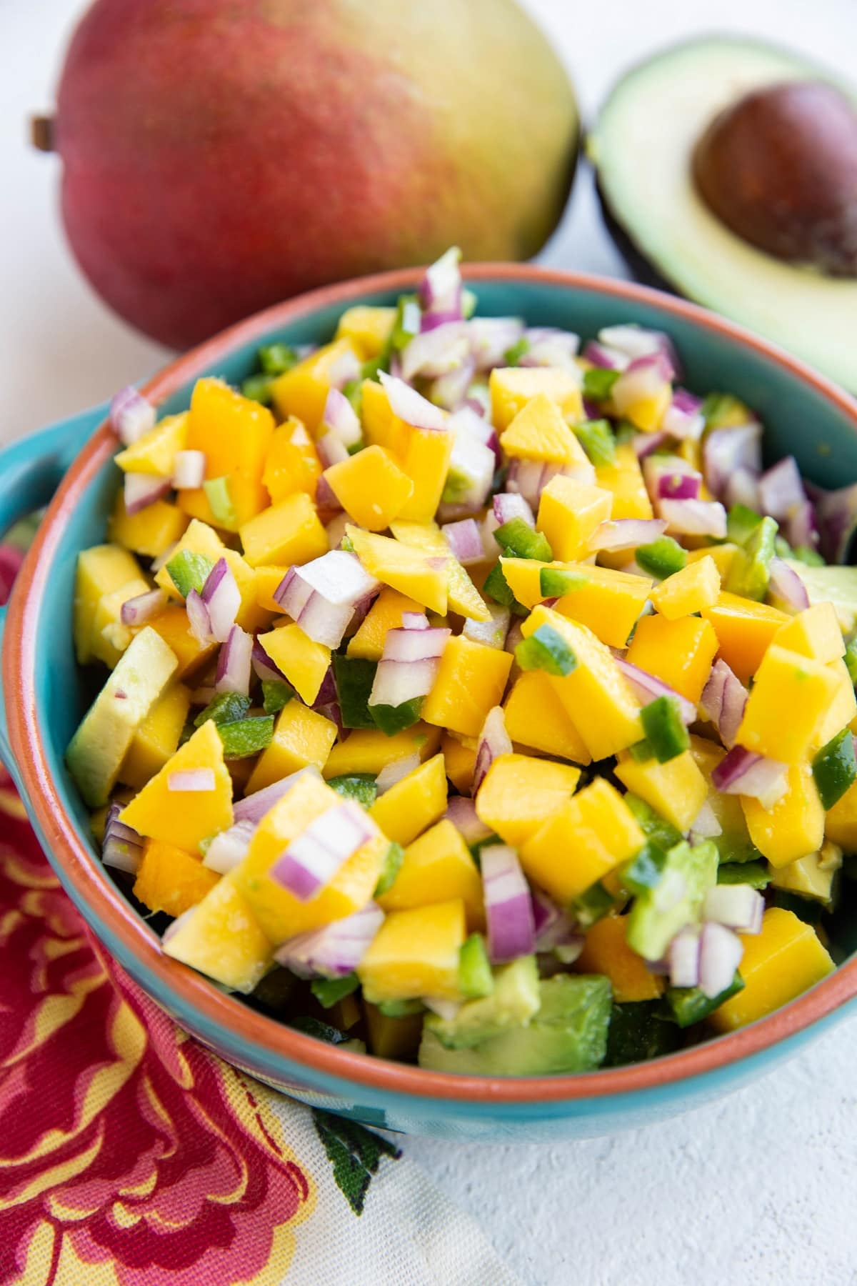 Blue bowl of mango avocado salsa, ready to be enjoyed on top of fish tacos or chicken breasts.