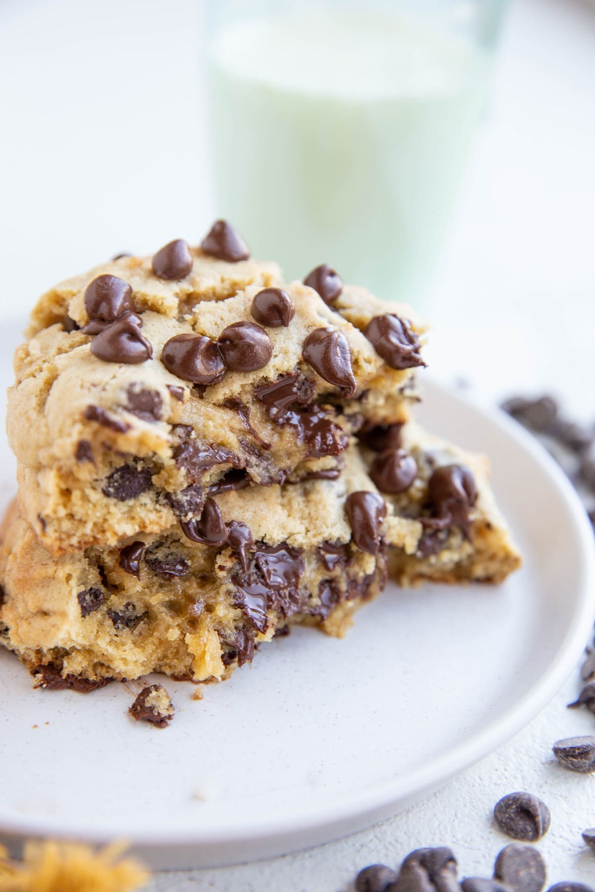 One big cookie cut in half and stacked on itself on a plate with milk in the background.