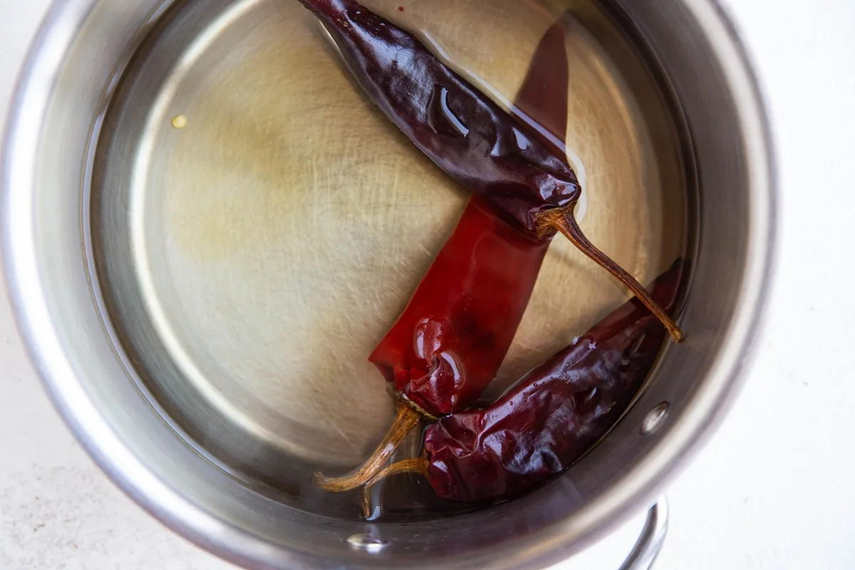 Dried red chilies in boiling water to become reconstituted.
