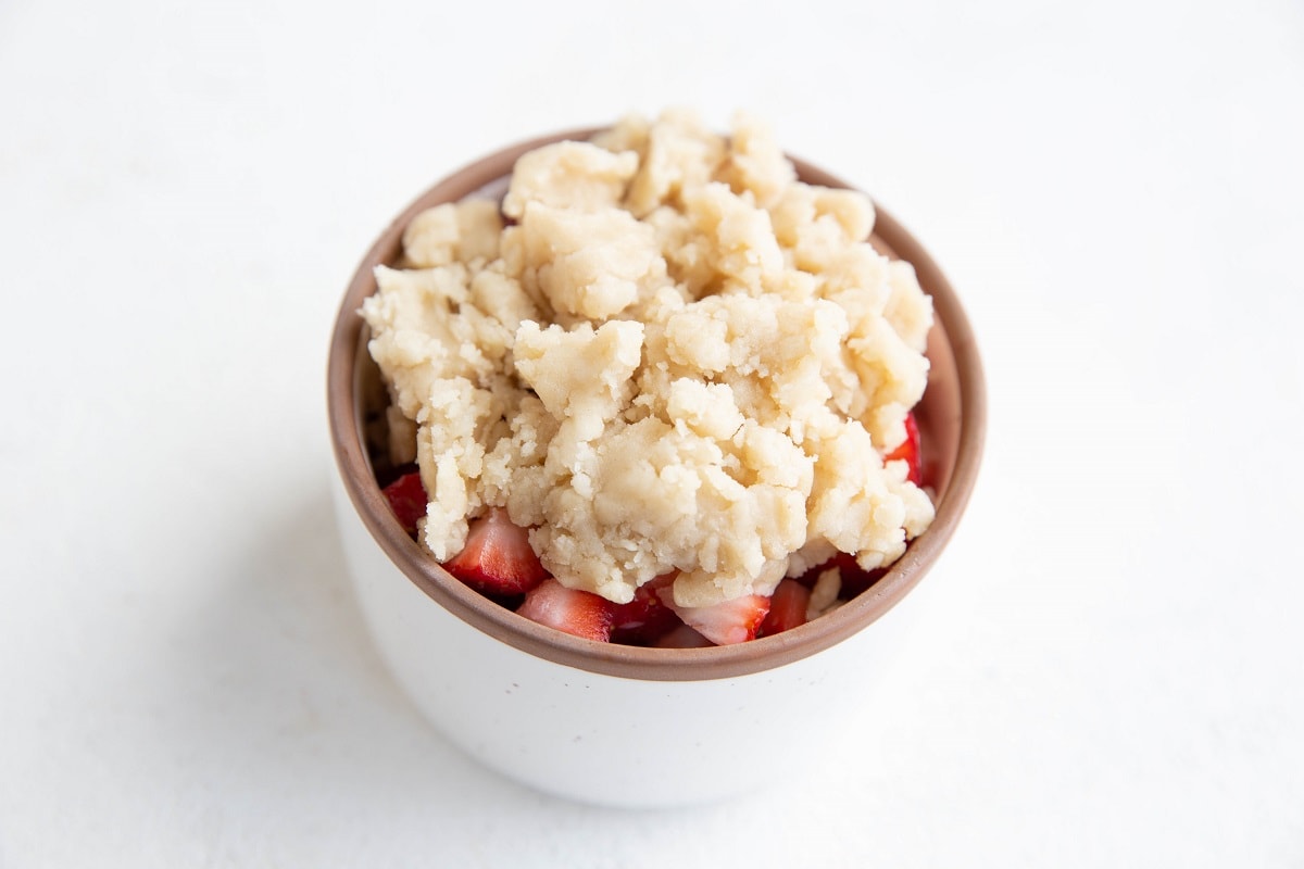 Ramekin with fresh chopped strawberries and cobbler topping on top.