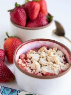 Single Serve Strawberry Cobbler in a white ramekin with fresh strawberries in the background.