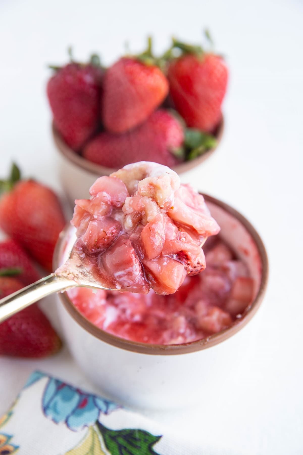 Gold spoon holding a spoonful of strawberry cobbler.