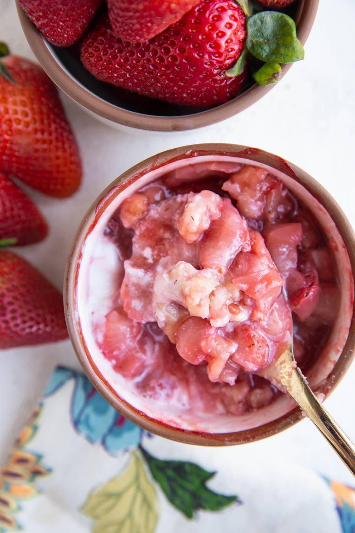 Spoon holding a spoonful of strawberry cobbler, ready to eat.