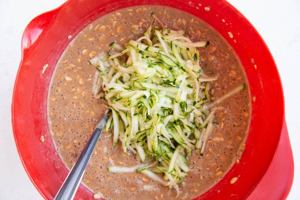 Zucchini oatmeal batter with shredded zucchini on top, ready to be mixed in.