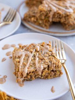 Slices of zucchini oatmeal on white plates with a plate of slices stacked in the background.