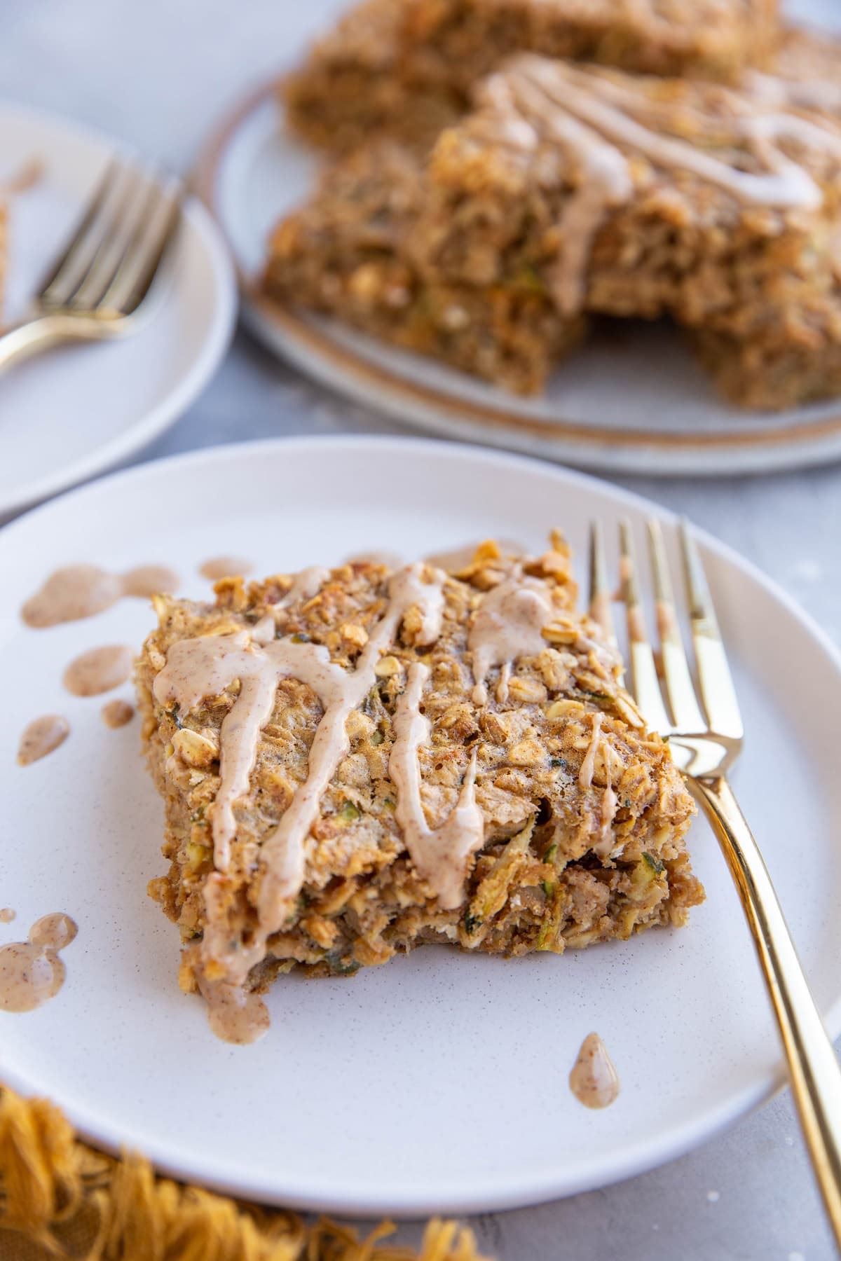 Slices of zucchini oatmeal on white plates with a plate of slices stacked in the background.