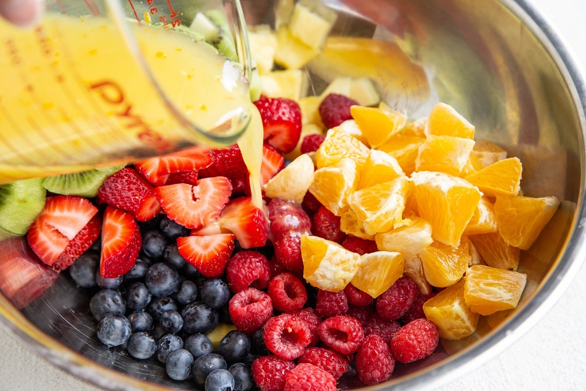 Pouring citrus dressing over the fruit.