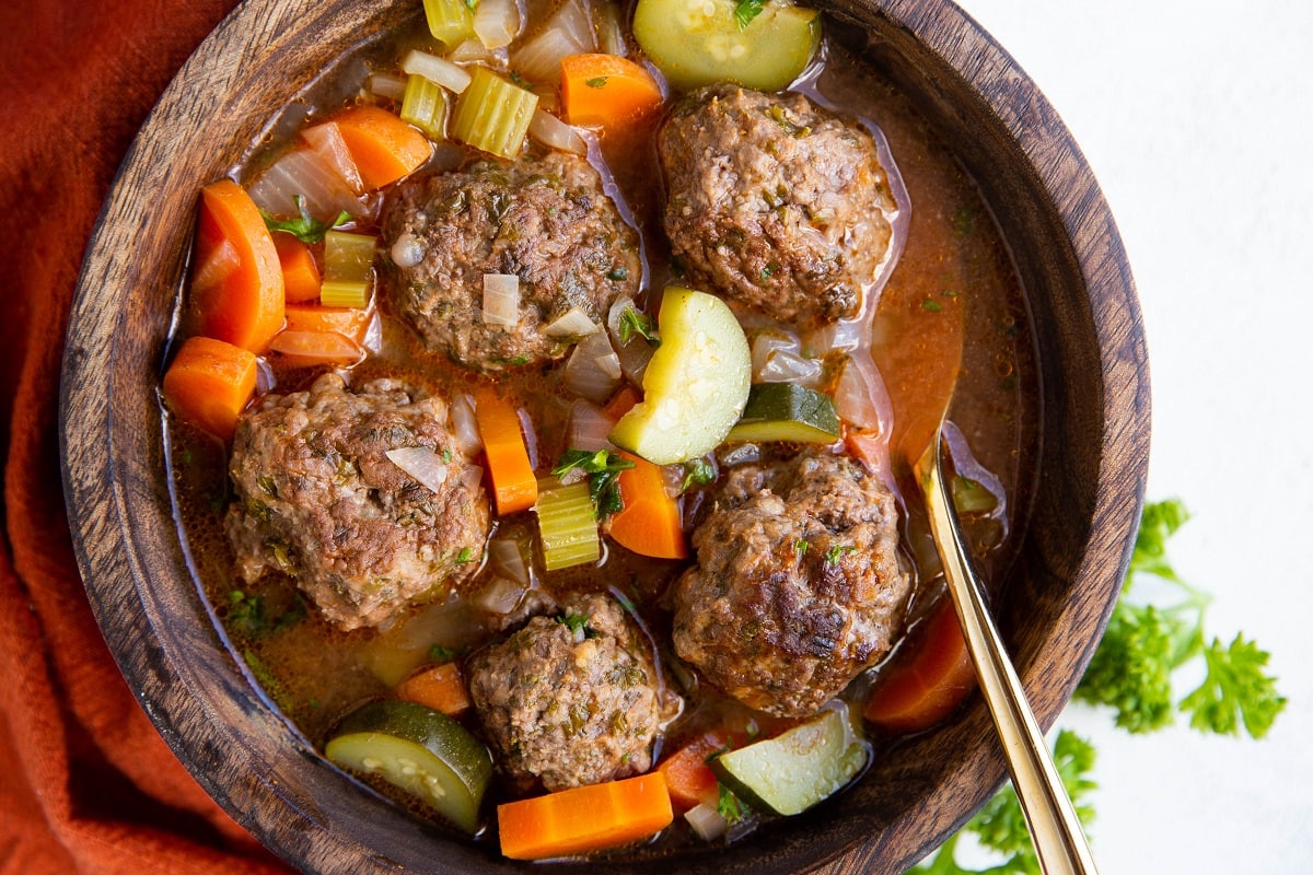 Bowl of albondigas soup with a golden spoon, ready to eat.