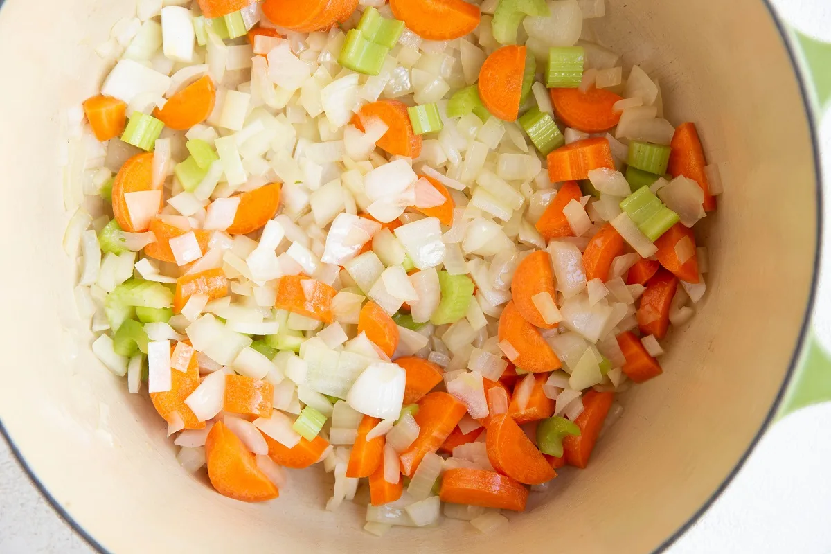 Onions, carrots, and celery sautéing in a large pot.