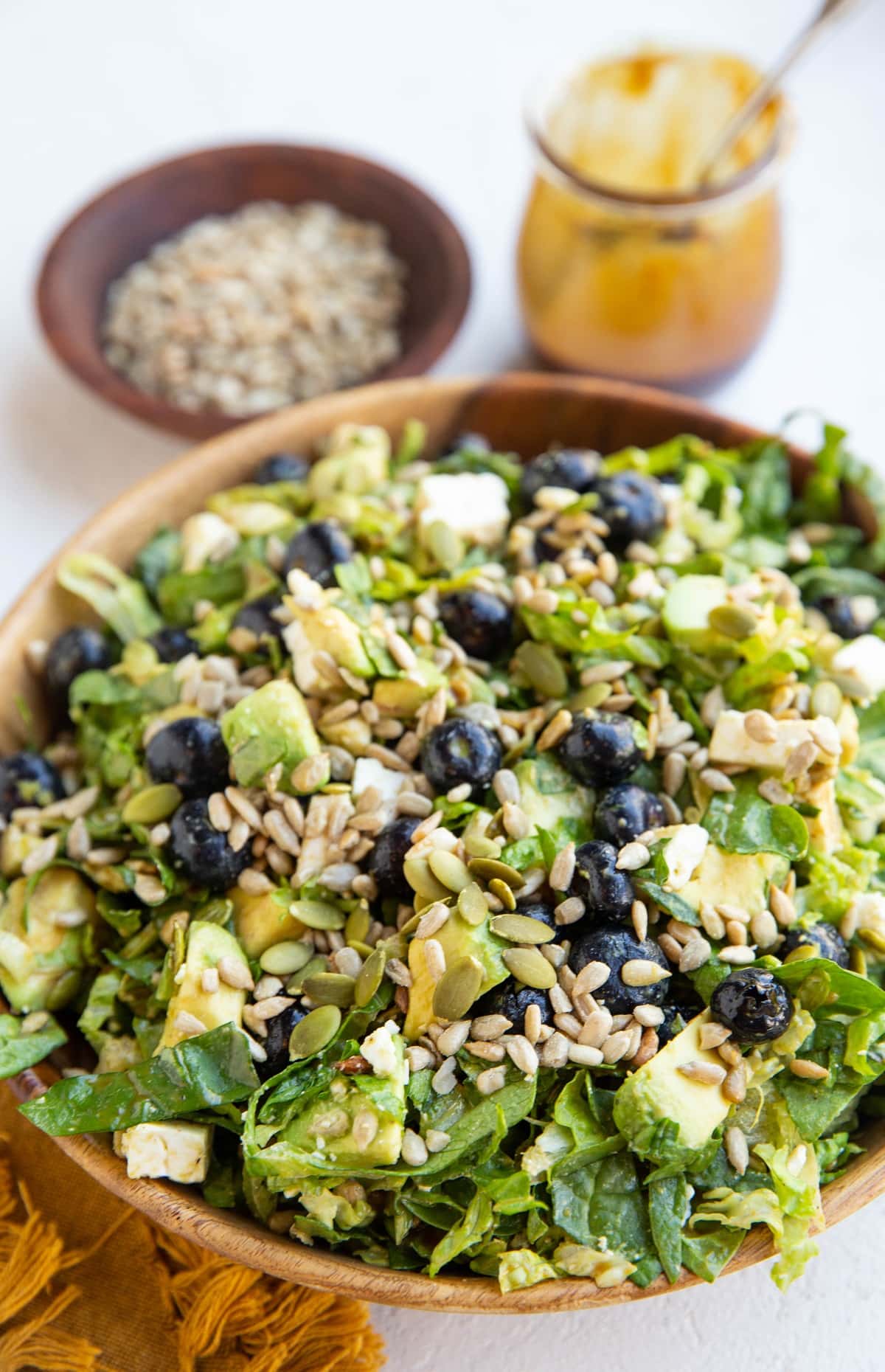 Big bowl of salad with salad dressing in the background.