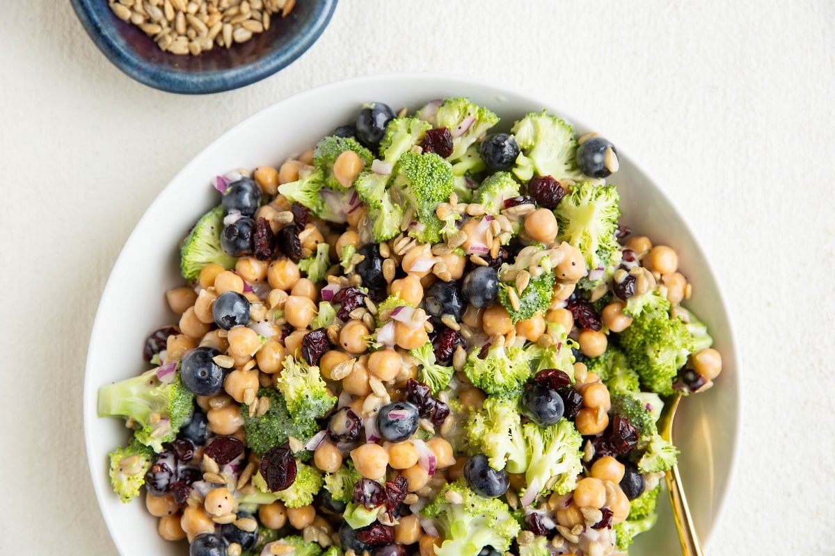Broccoli Chickpea Salad with sunflower seeds, blueberries, red onion and more in a white bowl