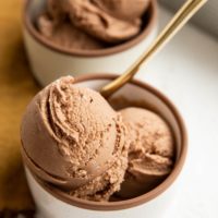 Two bowls of chocolate ice cream with a golden spoon.