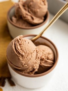 Two bowls of chocolate ice cream with a golden spoon.