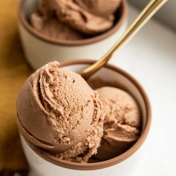 Two bowls of chocolate ice cream with a golden spoon.