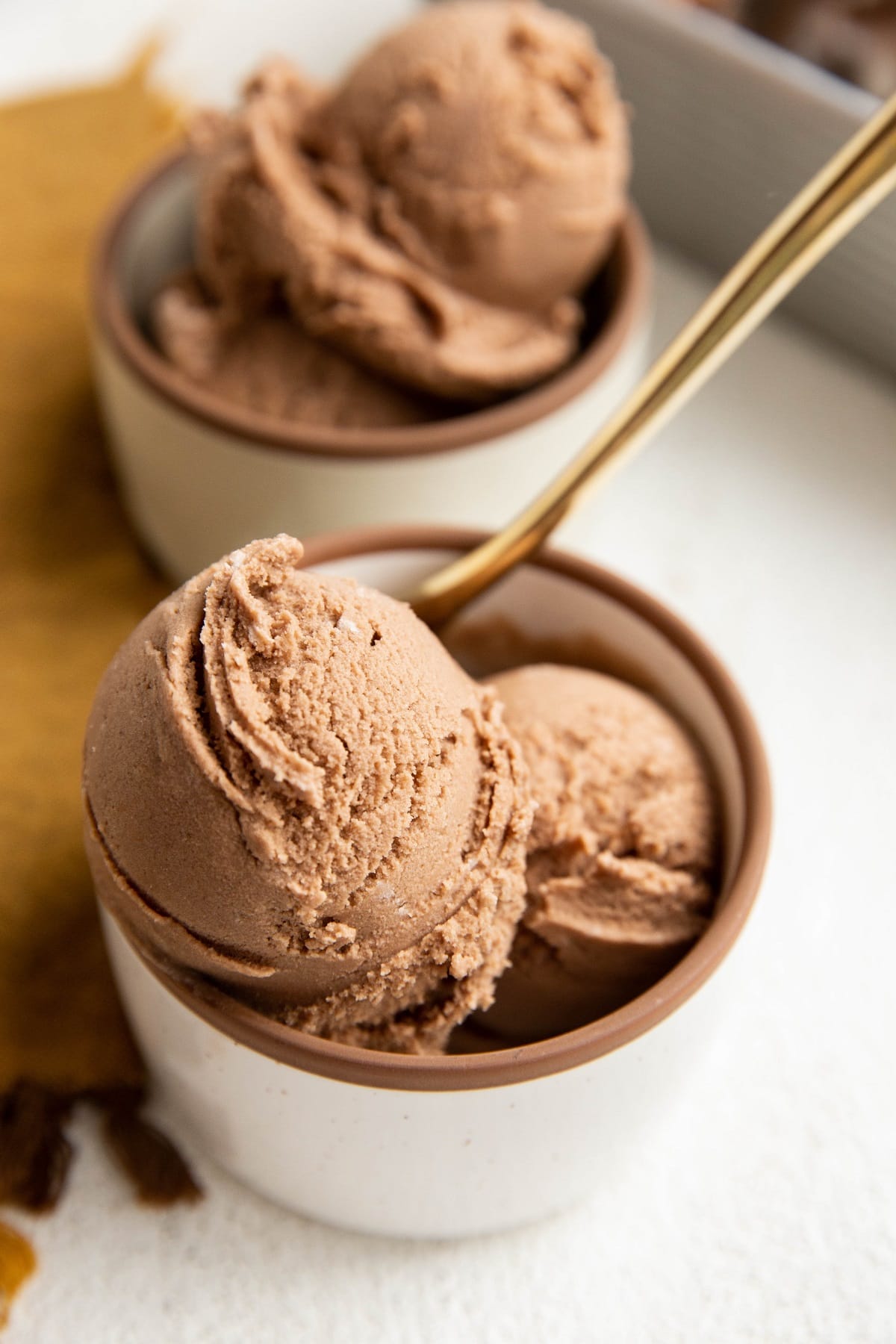 Two bowls of chocolate ice cream with a golden spoon.