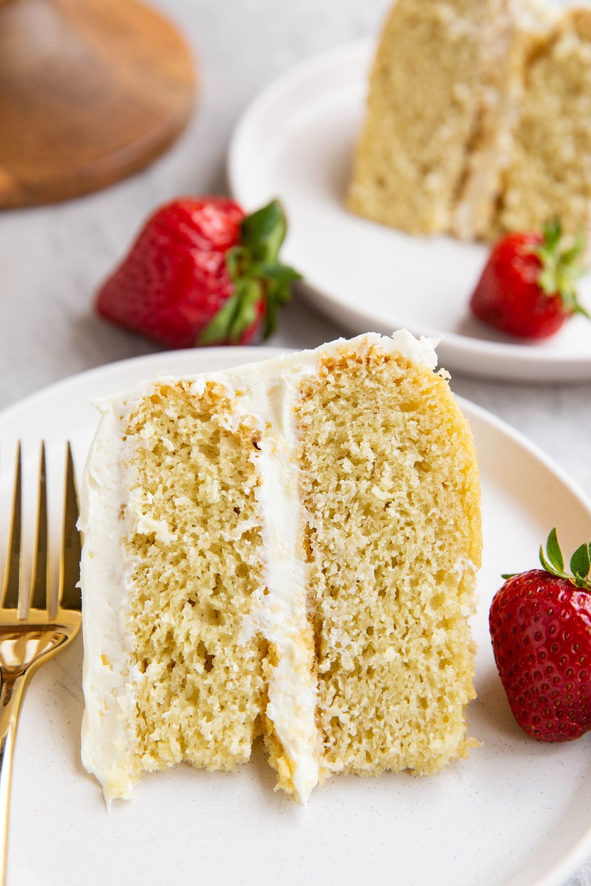 Two slices of vanilla layer cake on two plates.