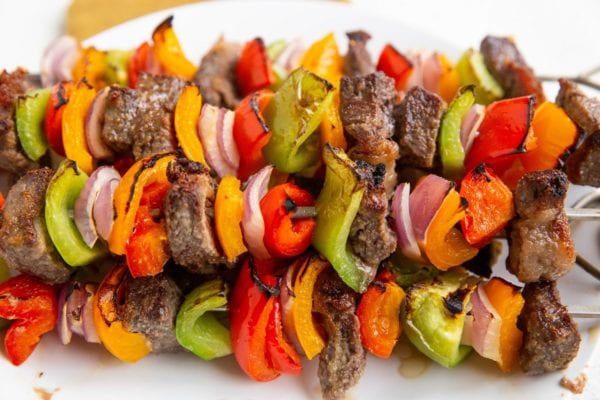 White plate with beef shish kabobs stacked on top.