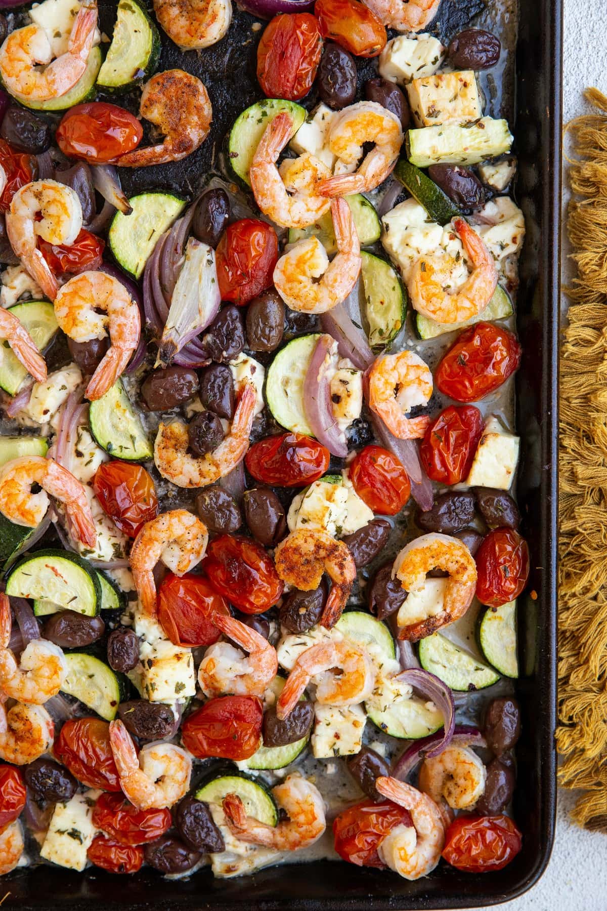 Large baking sheet with shrimp and vegetables for a complete meal, fresh out of the oven.