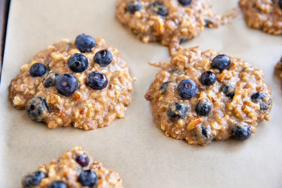 Lumps of cookie dough on a baking sheet lined with parchment paper.