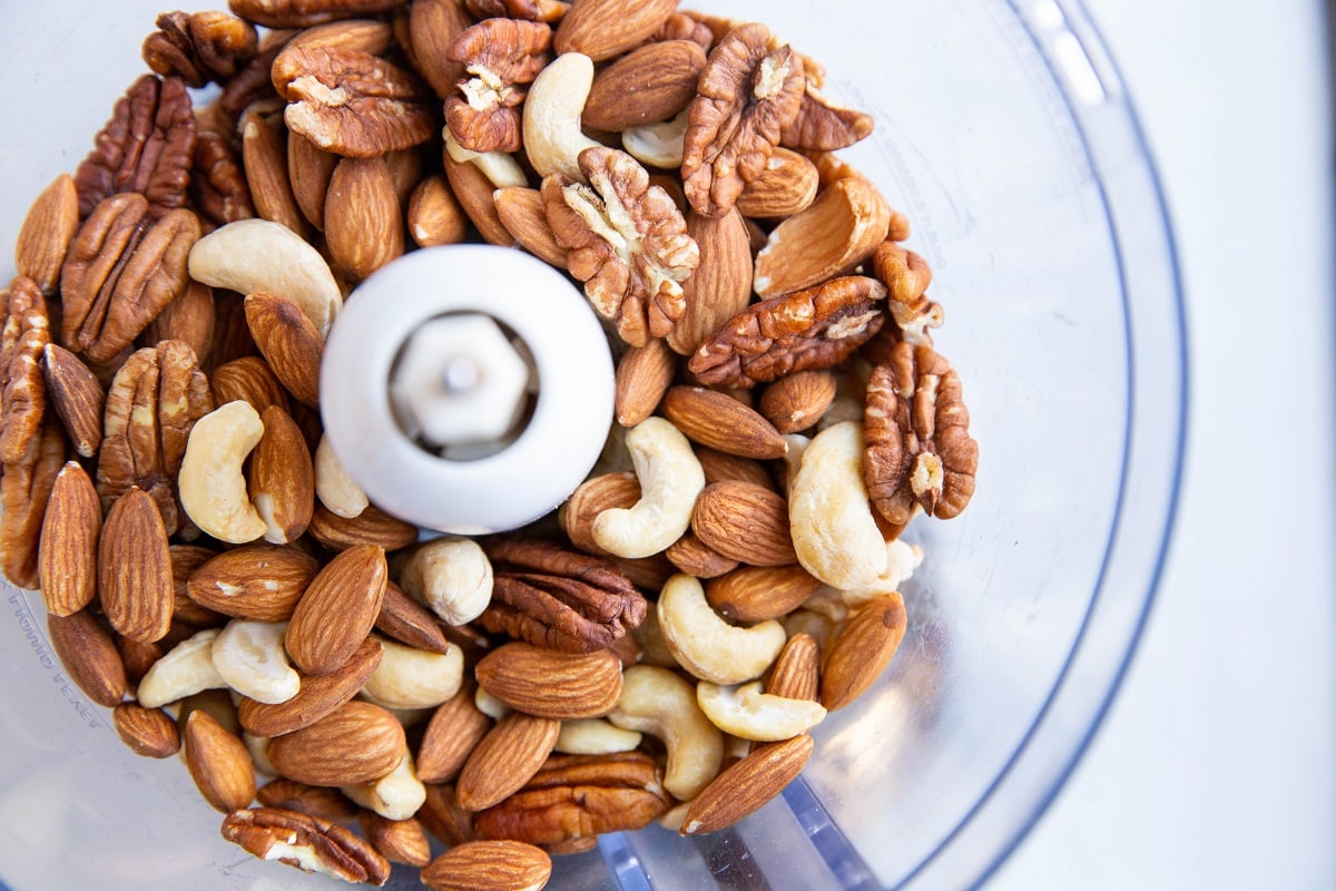 Mixed nuts in a food processor, ready to be ground up.