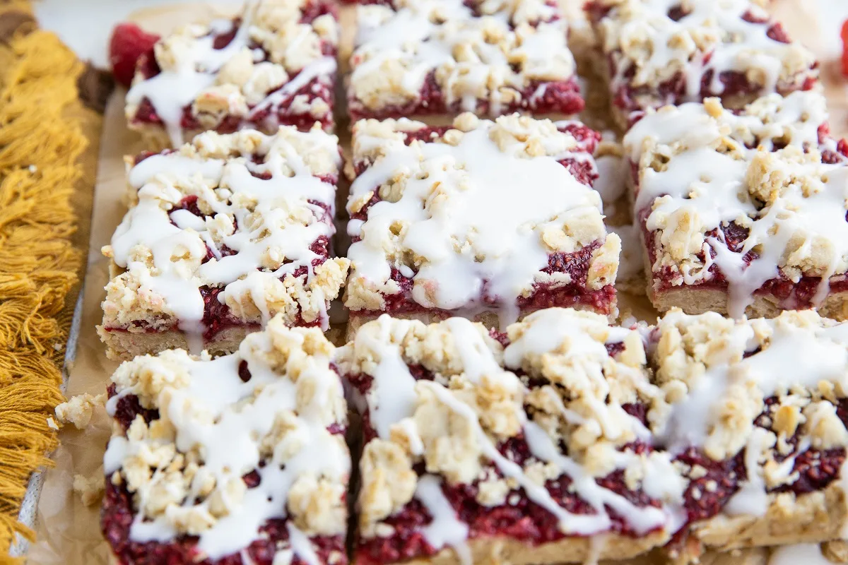 Raspberry crumb bars with a simple glaze, cut into individual squares and ready to serve.