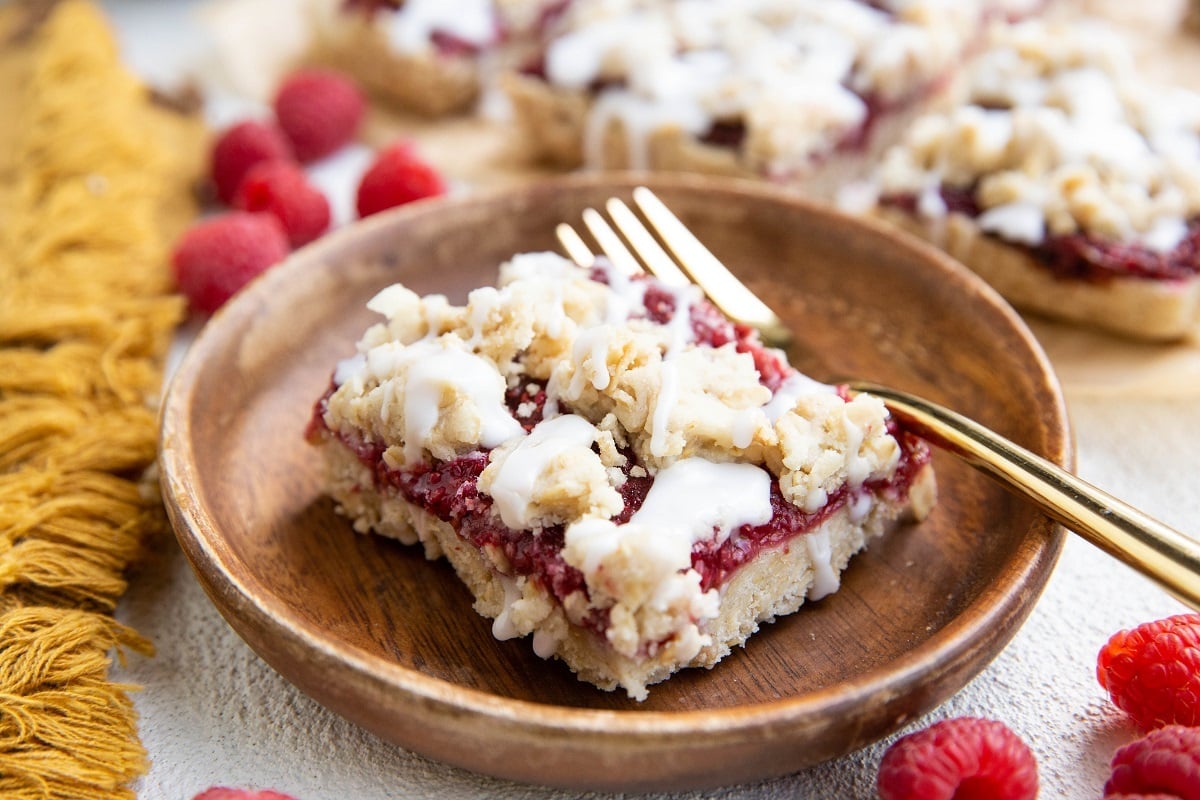 Slice of raspberry crumb bar on a wooden plate.