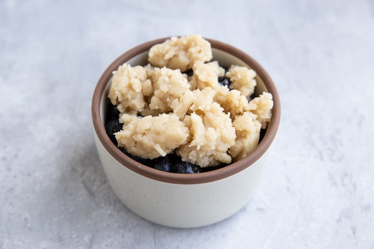 Small ramekin with blueberries and crumble topping inside, ready to bake.