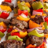 Plate of beef kabobs stacked on top of each other, fresh off the grill.