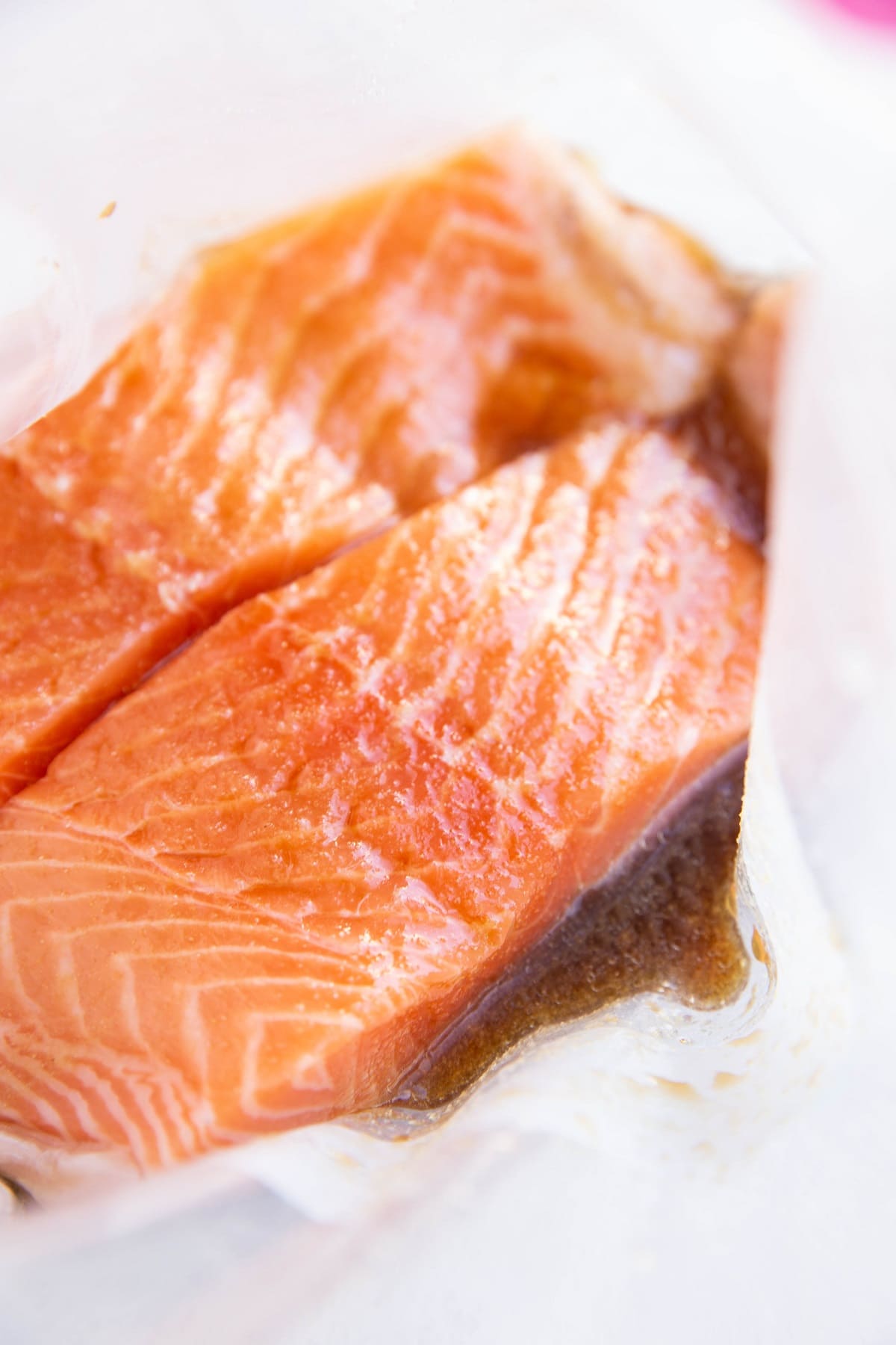 Two raw salmon filets in a zip lock bag with marinade.