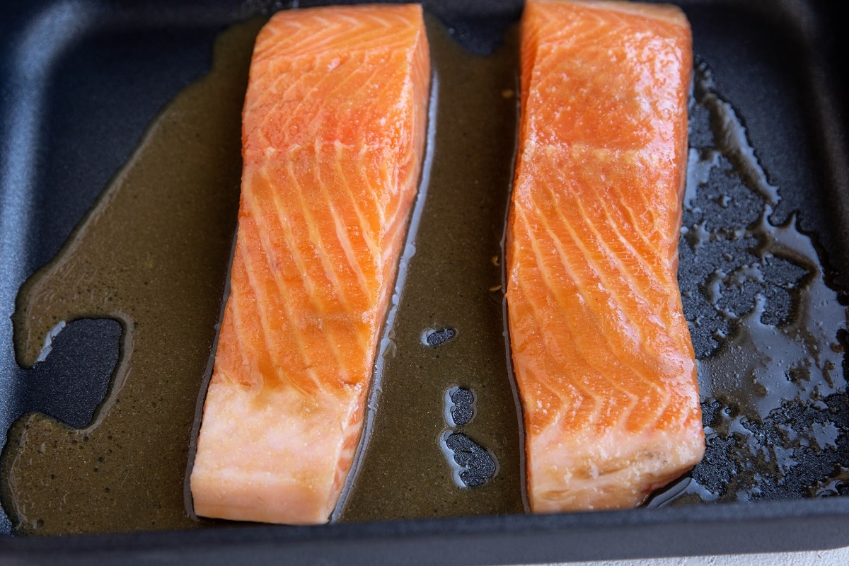 Salmon filets with marinade in a baking dish.