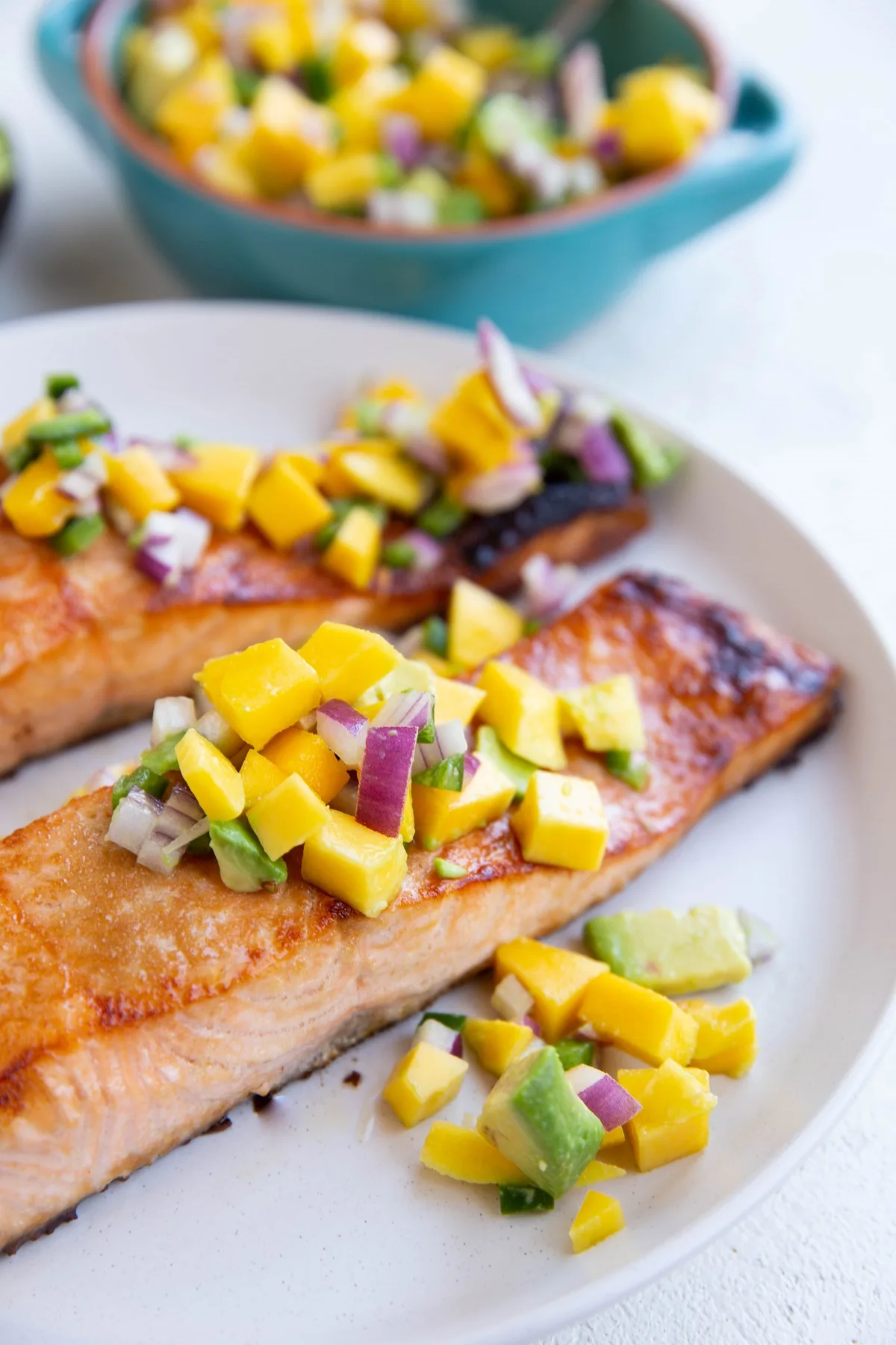 Close up of two salmon filets with mango salsa.