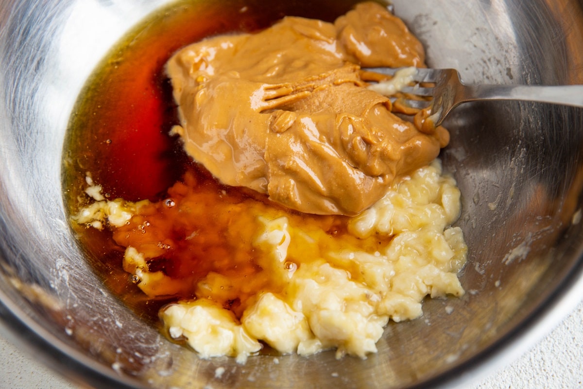 Almond butter, pure maple syrup and mashed banana in a mixing bowl.