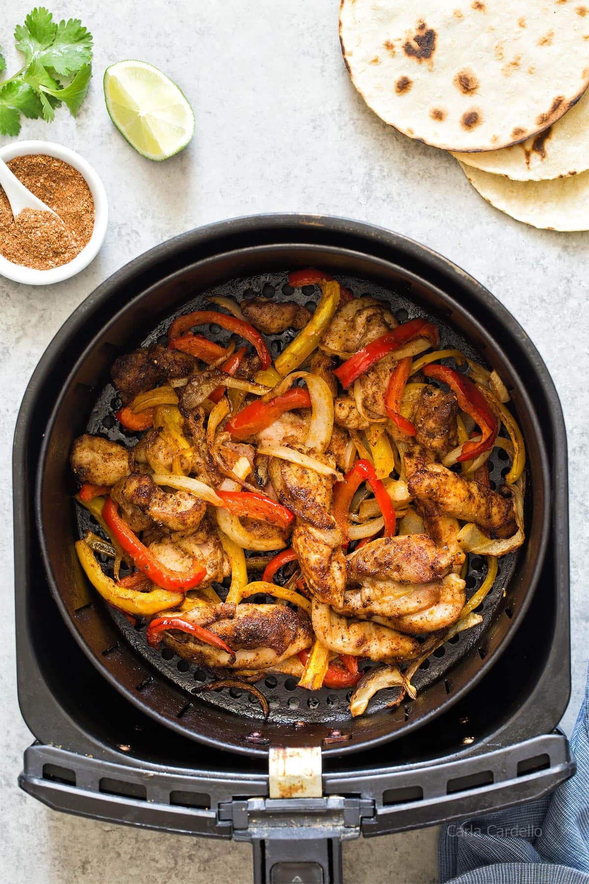 Air fryer basket with chicken fajitas inside