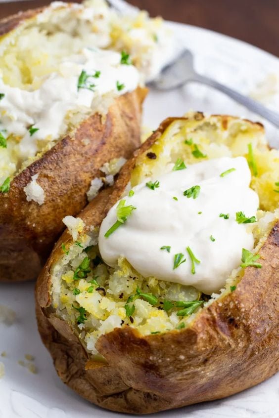 Baked potatoes on a white plate with toppings.