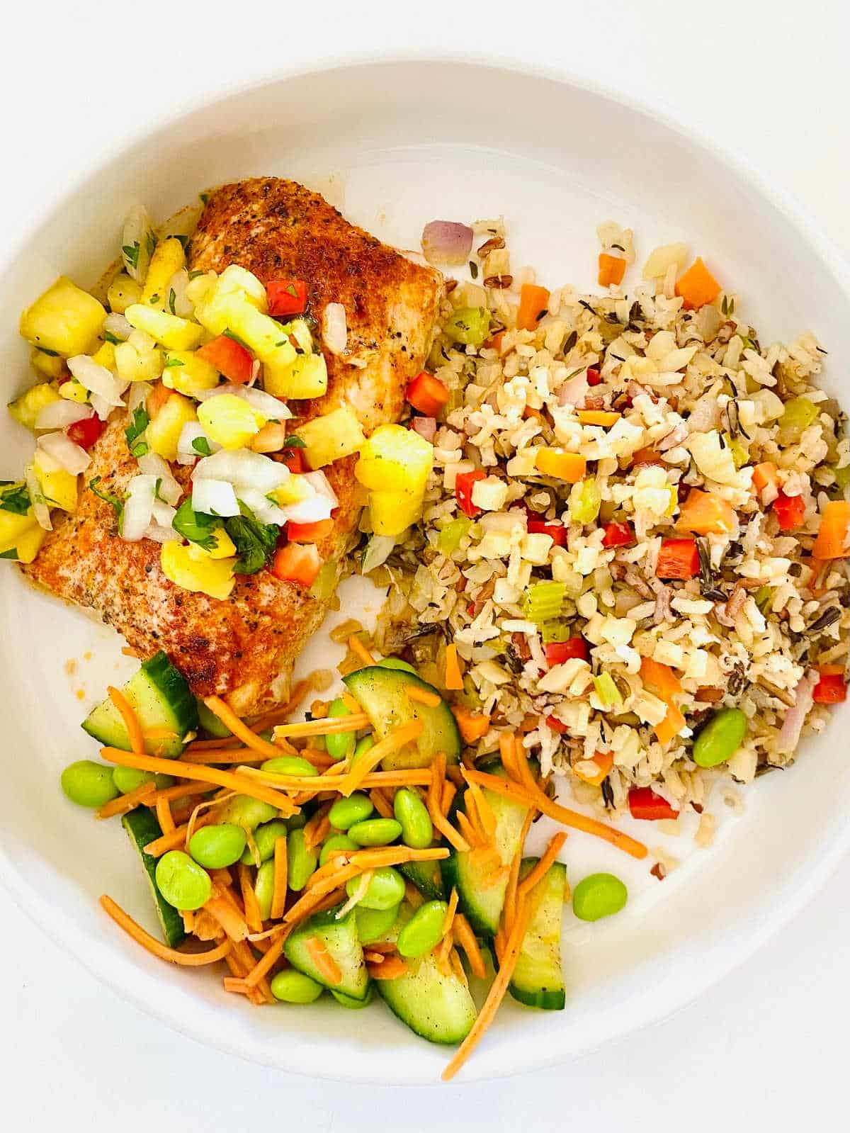 Mahi mahi on a plate with veggies and wild rice