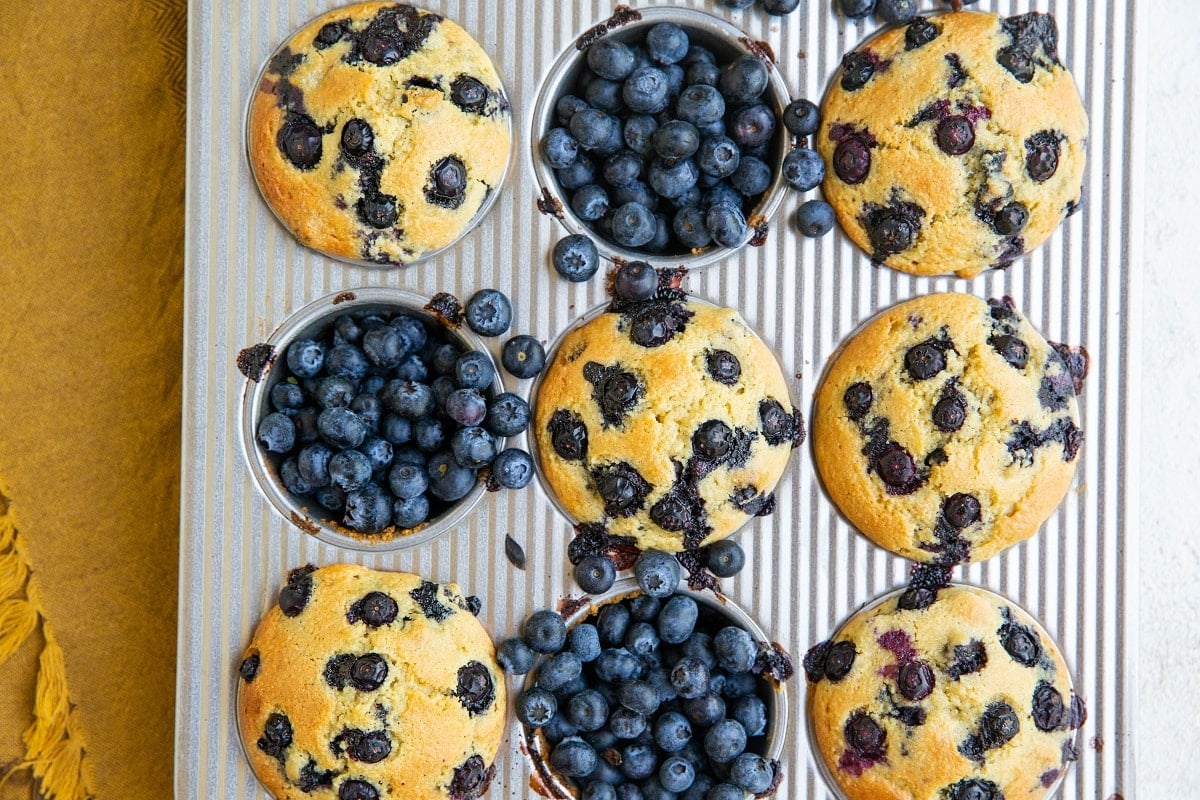 Muffin tin with blueberry muffins inside.