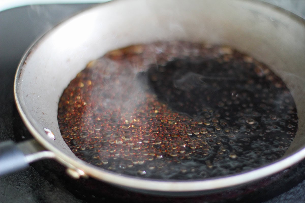 Balsamic vinegar reducing in a small skillet.