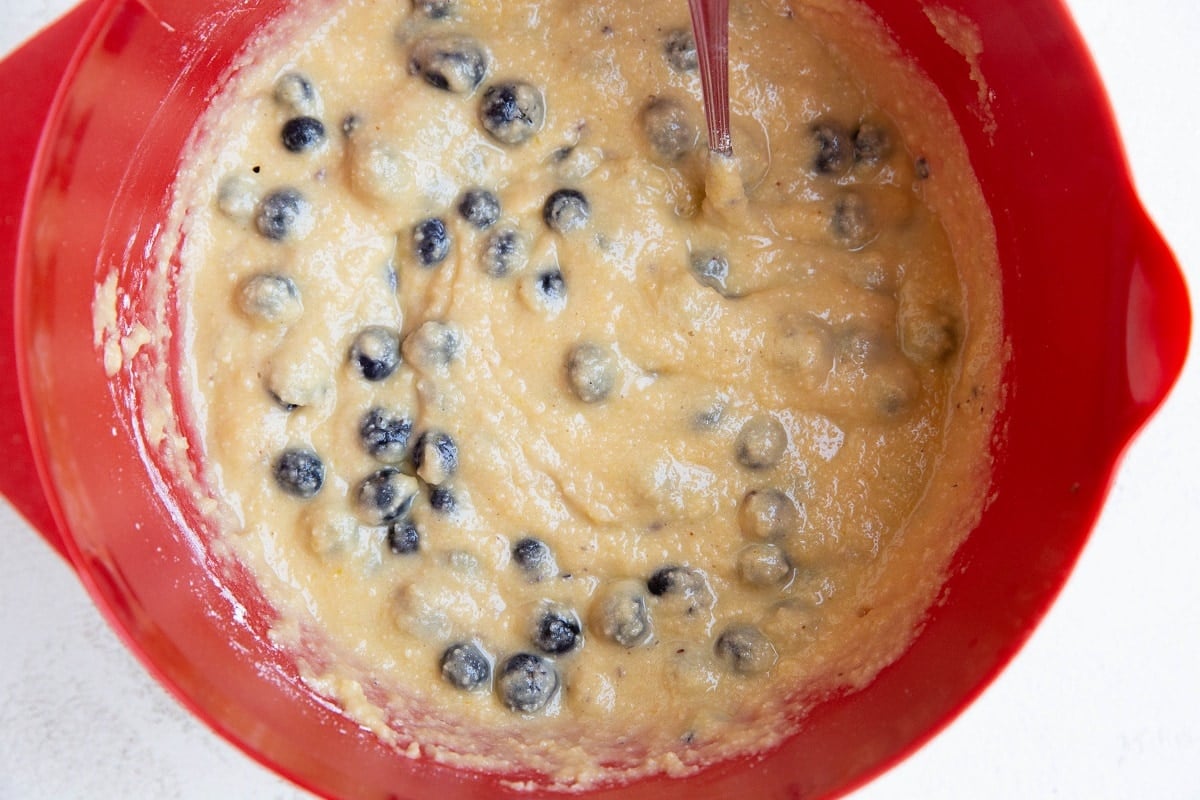 Blueberry muffin batter in a red mixing bowl.