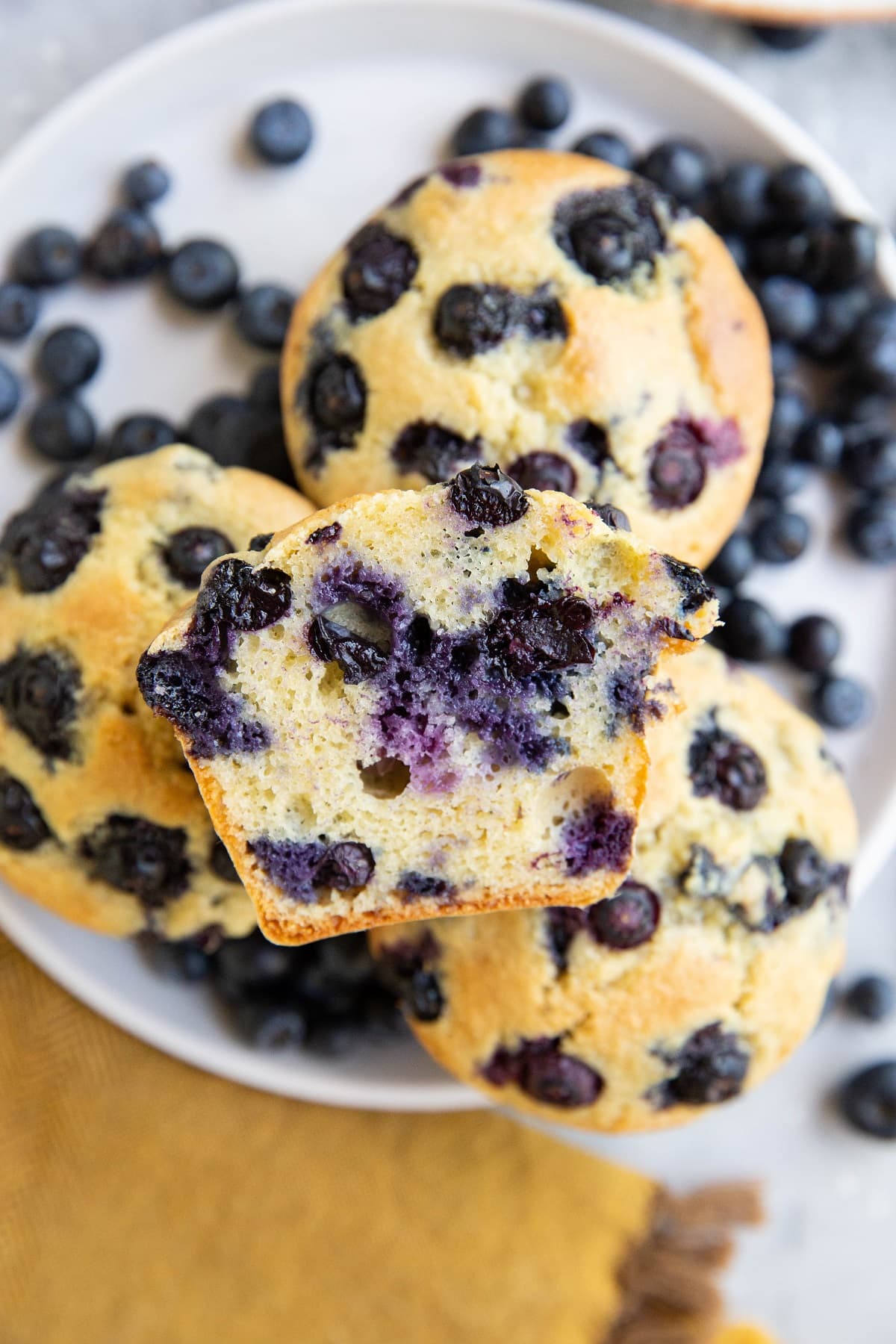 White plate of muffins with one sliced in half so you can see the inside.