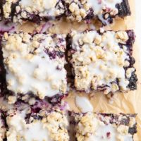 Blueberry crumb bars cut on a piece of parchment paper.