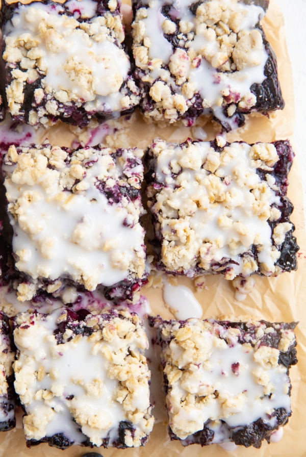 Blueberry crumb bars cut on a piece of parchment paper.