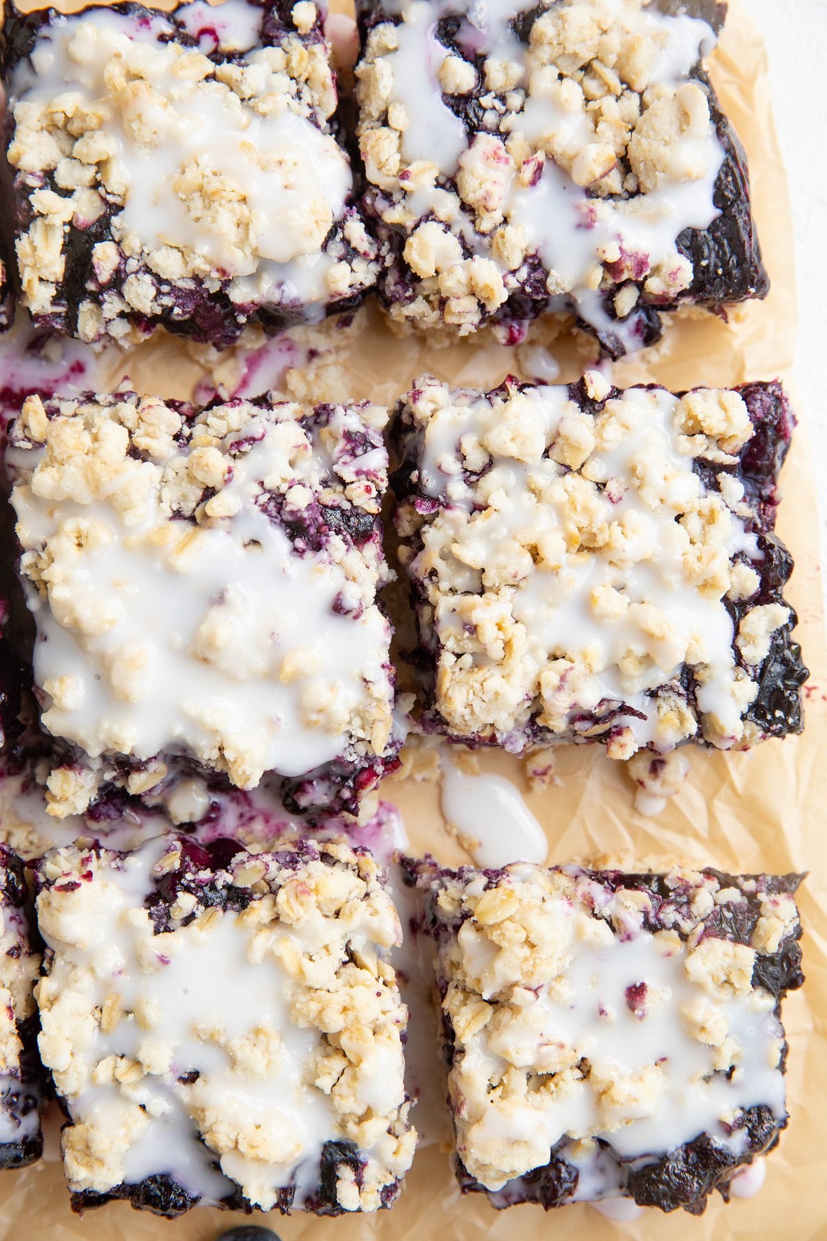 Blueberry crumb bars cut on a piece of parchment paper.