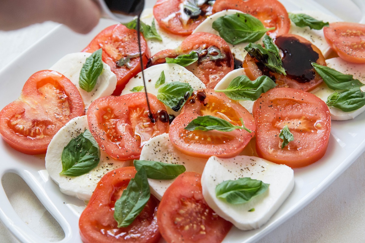 Pouring reduced balsamic over a caprese salad