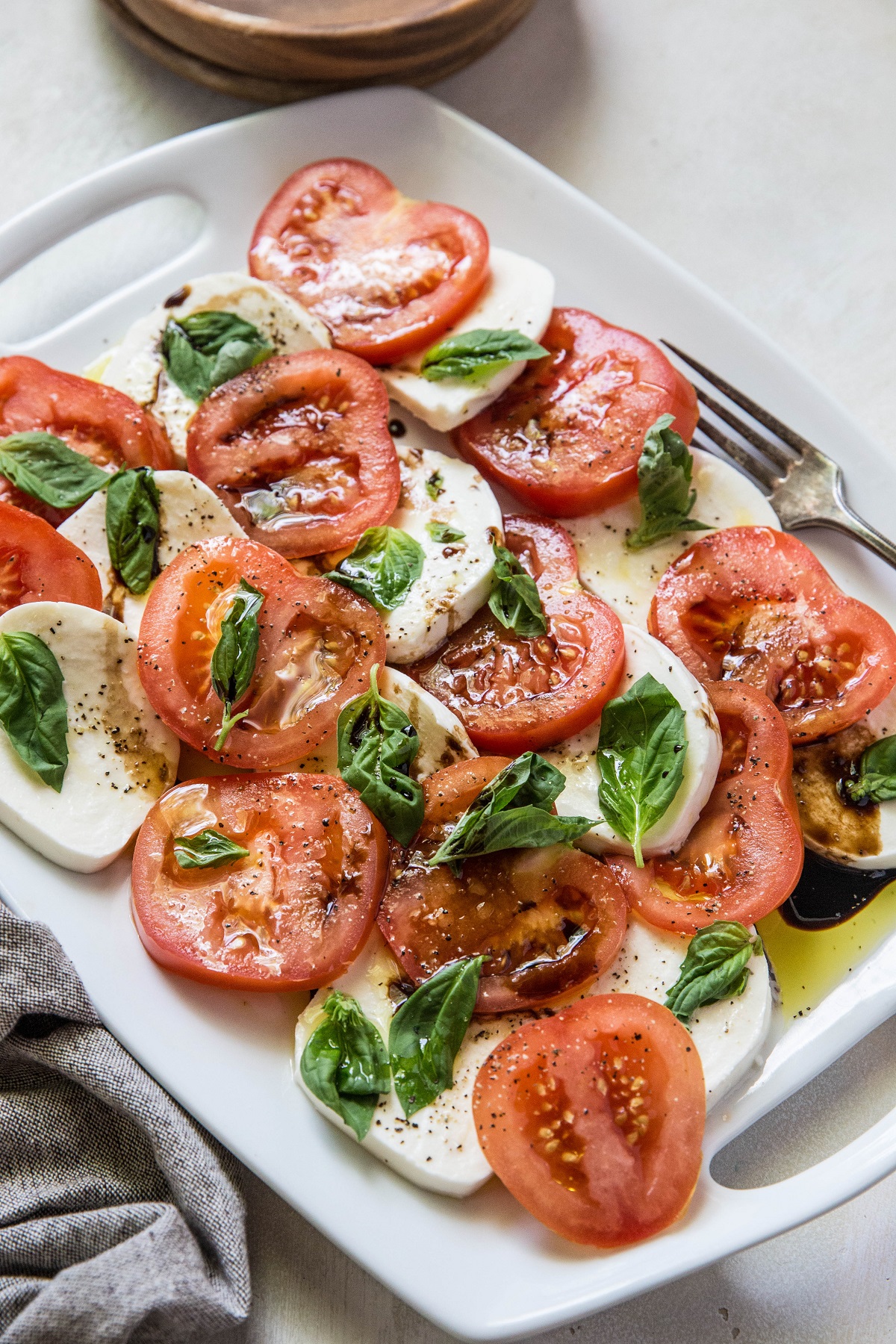 Slices of tomatoes, cheese and basil on a serving plate with oil and vinegar.