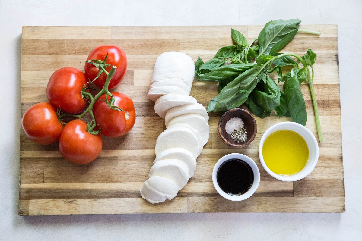 Caprese salad ingredients on a wooden cutting board.