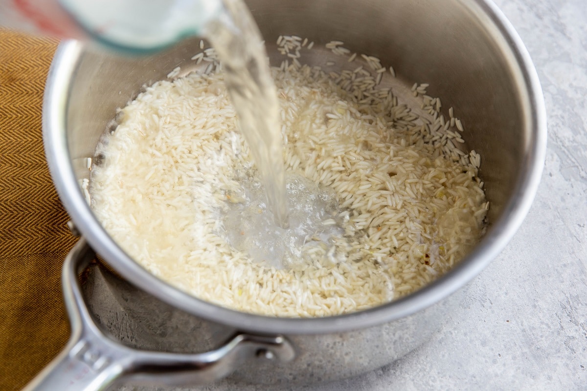 Pouring water into the saucepan with rice.