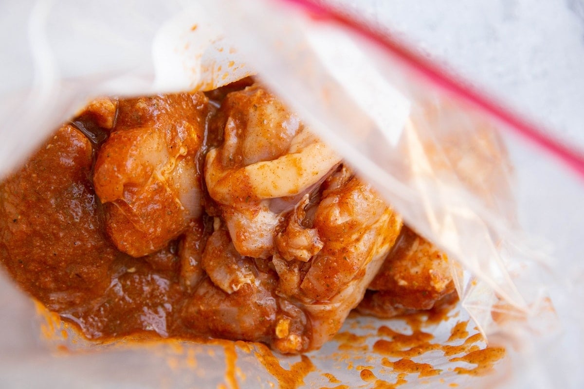 Raw chicken thighs and marinade in a plastic bag to marinate.