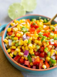 Blue bowl full of corn salsa with a fresh lime in the background.