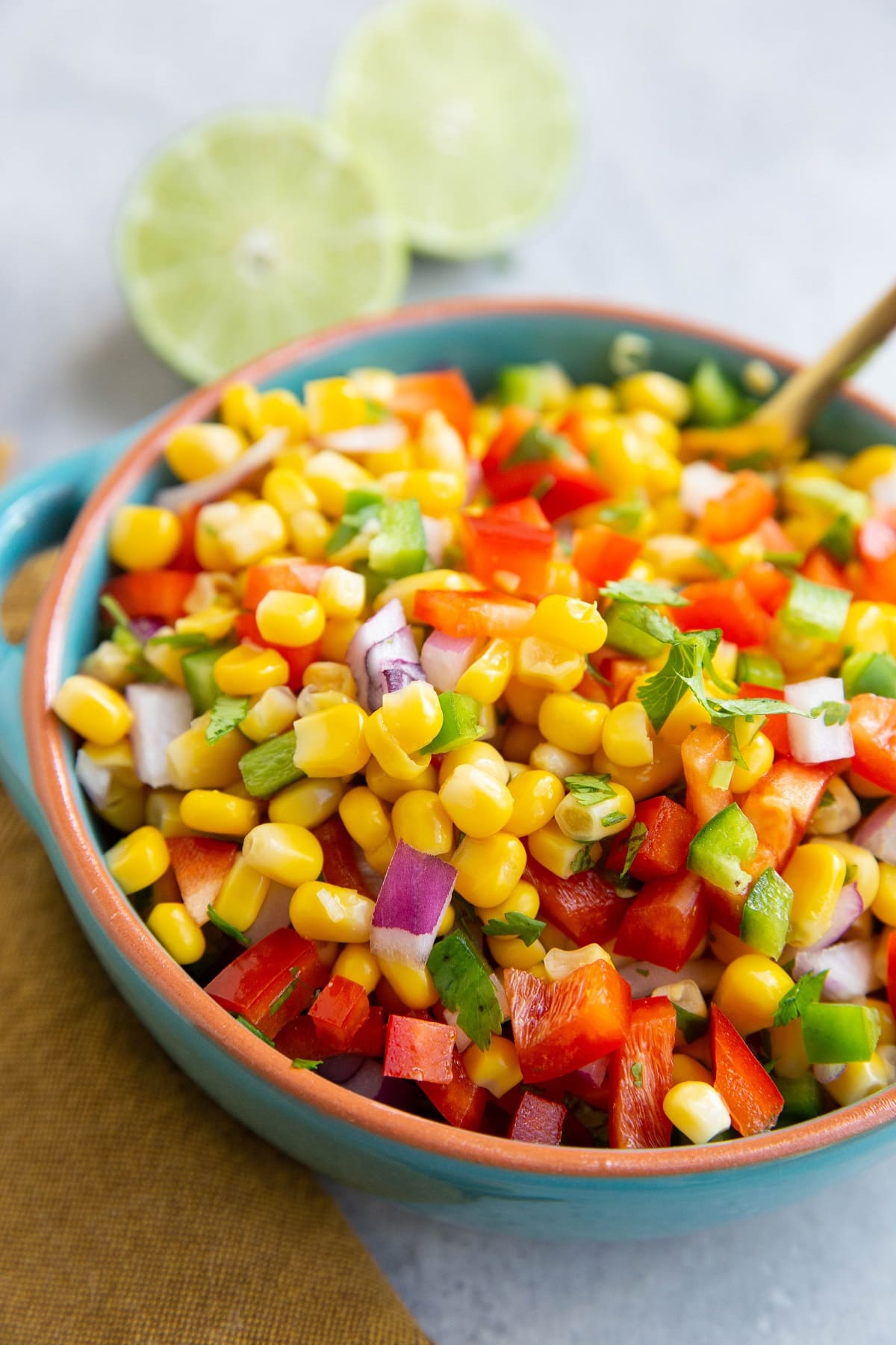 Blue bowl full of corn salsa with a fresh lime in the background.